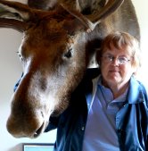 Pam in the visitor center with the moose looking over he shoulder.